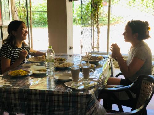 dos mujeres sentadas en una mesa comiendo comida en Sumudu Modern Villa en Tangalle