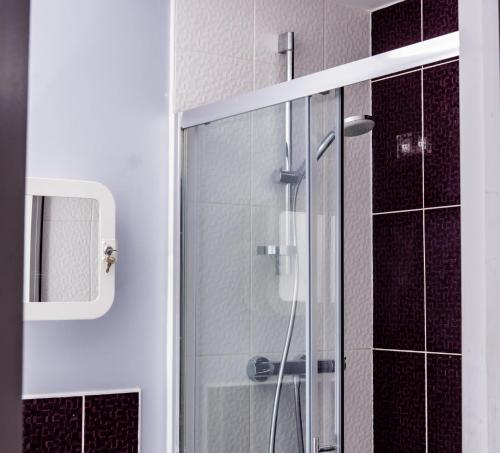 a glass shower in a bathroom with black tiles at Divine Stay in Coventry