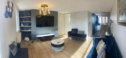 a living room with a couch a table and a tv at LuxuryJo BnB - Chambre dans un appartement spacieux et charmant in Roanne