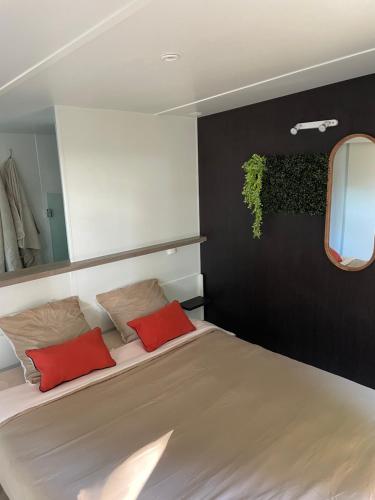 une chambre avec un grand lit avec deux oreillers rouges dans l'établissement Chant des Oiseaux ***, à Royan