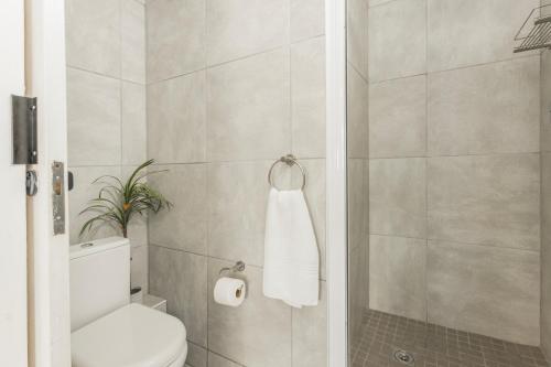 a bathroom with a white toilet and a shower at Ocean Pearl at Chakas Cove - Beachfront Apartment in Ballito