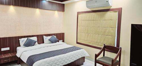 a bedroom with a bed and a chair and a window at Hotel Royal Wings in Elūr