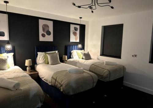 a bedroom with three beds and a flat screen tv at Apartment by DH ApartHotels in Peterborough