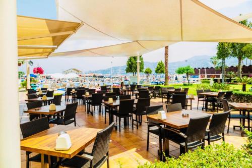 un restaurante con mesas de madera, sillas y sombrillas en Bel Azur Hotel - Resort en Jounieh