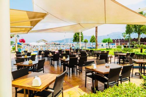 ein Restaurant mit Holztischen, Stühlen und Sonnenschirmen in der Unterkunft Bel Azur Hotel - Resort in Jounieh