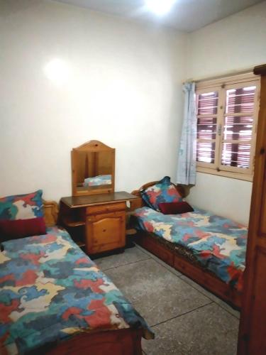 sypialnia z 2 łóżkami, biurkiem i lustrem w obiekcie Appartement à Meknès w mieście Meknès
