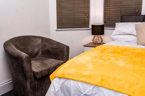- une chambre avec une chaise et un lit avec une couverture jaune dans l'établissement Divine Stay, à Coventry