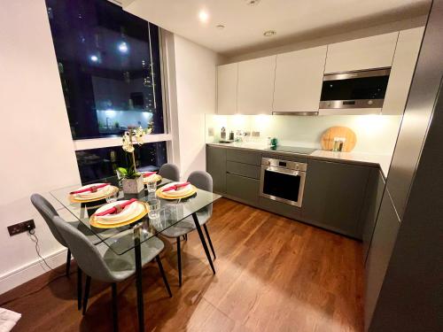 eine Küche mit einem Glastisch und Stühlen sowie eine Küche mit einer Theke in der Unterkunft Luxury Modern 2 Bed Flat with Balcony + City View - Canary Wharf City Center in London