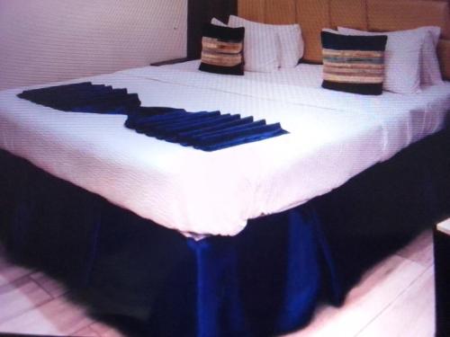 a large bed with black and white sheets and pillows at VILLA TOSCANA asaba in Okpanam
