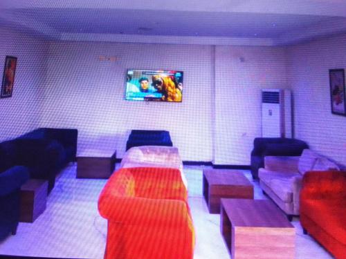 a living room with couches and a tv on the wall at VILLA TOSCANA asaba in Okpanam