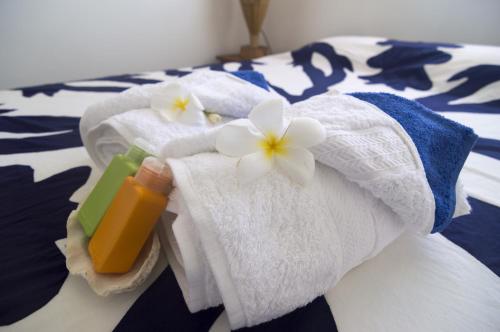 uma cama com toalhas e uma garrafa de sabão e flores em Va'a i te Moana em Avatoru