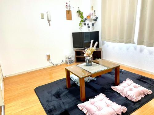 a living room with a coffee table and two pink pillows at FUKUOKA airport line Ijiri st self check in apartment in Fukuoka