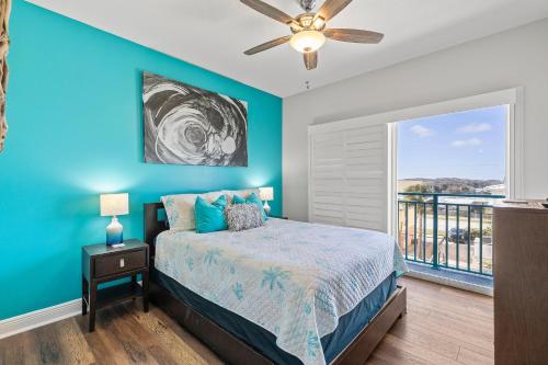 a blue bedroom with a bed and a balcony at The Wave 302 in New Smyrna Beach