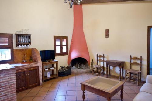 sala de estar con chimenea, sofá y mesa en Paraje del Hueznar, en Cazalla de la Sierra