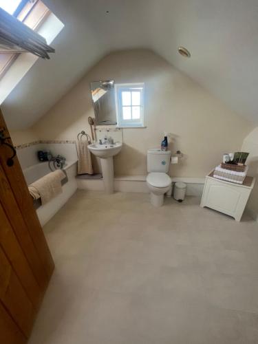a bathroom with a toilet and a sink and a mirror at Highcroft House in Corsham