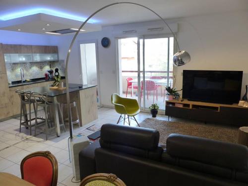 un salon avec un canapé et une télévision et une cuisine dans l'établissement Résidence OPALINE. Bel appartement avec grande terrasse pour 4 personnes, à Capbreton