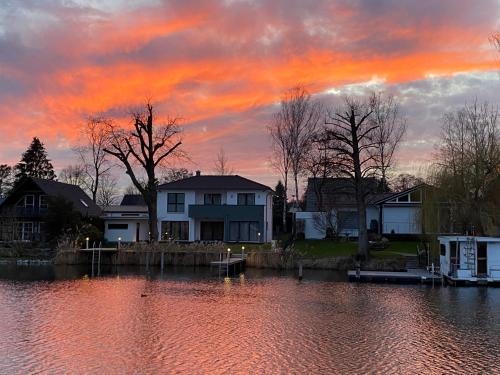 a sunset over a body of water with houses at Ferienhaus mit Wasserterrasse - mit Sauna und Kamin - inklusive Nebenkosten in Wendisch Rietz