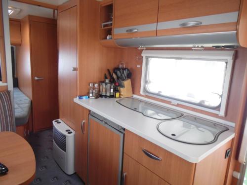 a kitchen with a sink and a window in an rv at Wohnwagen mit festem Vorzelt - all incl. in Fehmarn