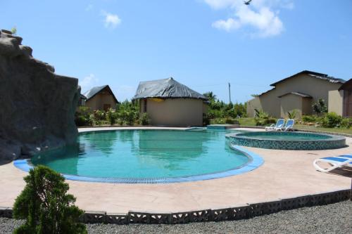 a swimming pool in a resort with two chairs at Unique Resort And Restaurant in Porbandar