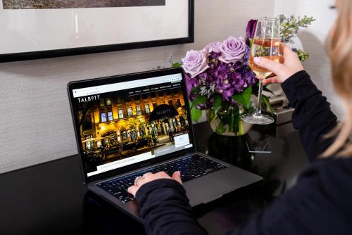 a woman holding a glass of wine next to a laptop computer at The Talbott Hotel in Chicago