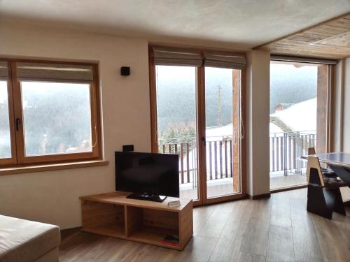 a living room with a flat screen tv and windows at Chalet MAOL Luxury Living in Valdidentro