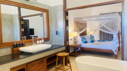 a bathroom with a tub and a sink and a bed at Sea Star Boutique Hotel in Hikkaduwa