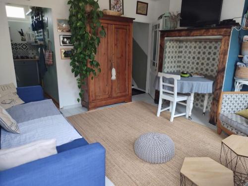 a living room with a blue couch and a table at L'Estaca Maison de pêcheur avec jardin bord de mer in Étretat