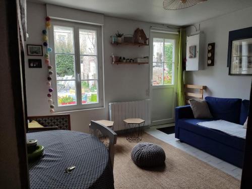 a living room with a blue couch and two windows at L'Estaca Maison de pêcheur avec jardin bord de mer in Étretat