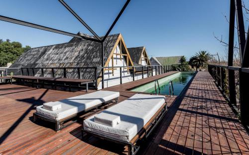 a deck with two beds and a swimming pool at Mousai Hotel Boutique in Capilla del Monte