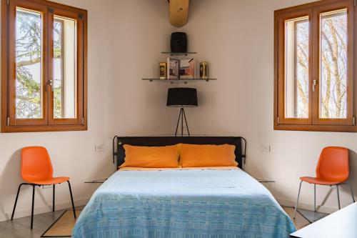 a bedroom with a bed and two orange chairs at Relais des Roches in Sona