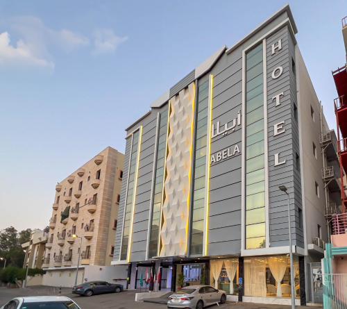 een groot gebouw met auto's geparkeerd op een parkeerplaats bij Abela Alhamra Jeddah - Palestine Branch in Jeddah