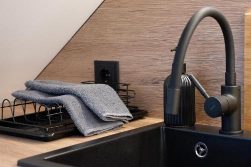 a black kitchen sink with a towel on a counter at Butas-loftas mieste, Kaunas in Kaunas