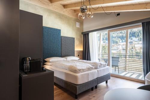ein Schlafzimmer mit einem Bett und einem großen Fenster in der Unterkunft Garnì La Violetta in Soraga