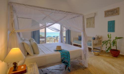 a bedroom with a canopy bed with a view of the ocean at Chale Island Resort in Chale Island