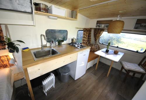a kitchen in an rv with a sink and a table at Cosy nest in animal rescue Monte dos Vagabundos in São Teotónio