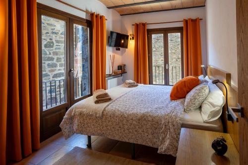 Schlafzimmer mit einem Bett und einem Fenster mit orangefarbenen Vorhängen in der Unterkunft Lo Petit Refugi in Camprodon