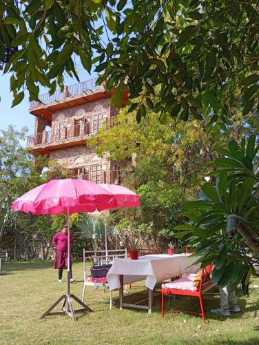 a table with a pink umbrella in front of a building at the secret garden in Pushkar