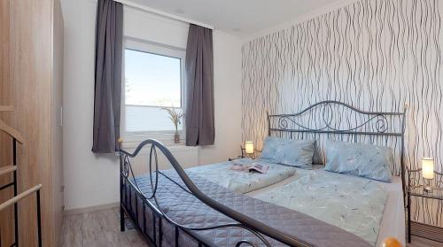 ein Schlafzimmer mit einem Bett mit blauen Kissen und einem Fenster in der Unterkunft Bungalow "Wiesenblick" in Trassenheide