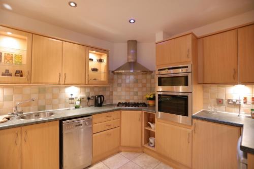 a kitchen with wooden cabinets and stainless steel appliances at Flat 6 in Edinburgh