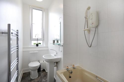 La salle de bains blanche est pourvue d'un lavabo, de toilettes et d'une baignoire. dans l'établissement Flat 6, à Édimbourg
