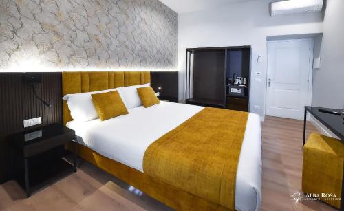 a bedroom with a large bed with yellow pillows at Alba Rosa Rooms in Rome