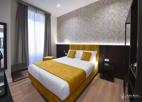 a bedroom with a large bed with a yellow blanket at Alba Rosa Rooms in Rome