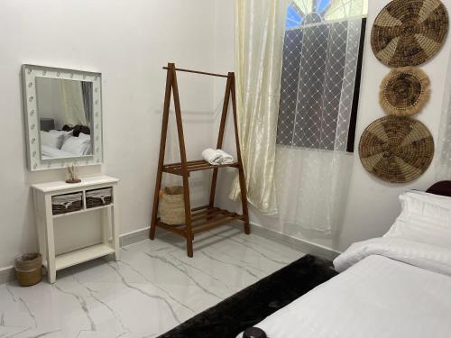 a white bedroom with a bed and a mirror at Nashu House Stone Town in Ngambo