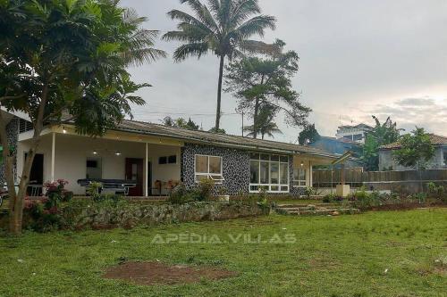 a house with a palm tree in front of it at Villa DBusso Apedia, 3 BR, SP, Billiard, Karaoke in Kopo 2