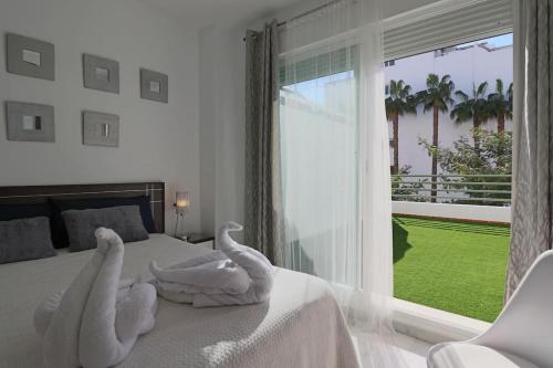 a bedroom with towels on a bed with a large window at Apartamento Junto al campo de golf in El Portil