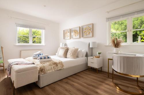 a white bedroom with a bed and two windows at Snowdrop - Connect to the Nature in the Hot Tub in Blandford Forum