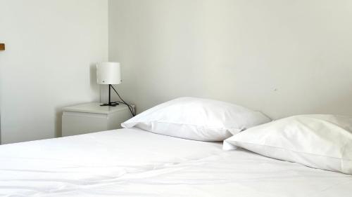 ein weißes Bett mit zwei Kissen und einer Lampe in der Unterkunft N254 - Numana, cielo-terra con meraviglioso giardino vista mare in Numana