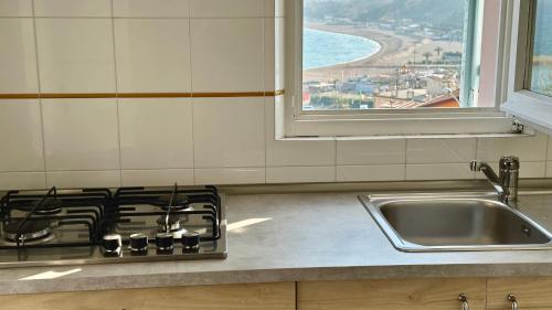 eine Küche mit einem Herd, einem Waschbecken und einem Fenster in der Unterkunft N254 - Numana, cielo-terra con meraviglioso giardino vista mare in Numana