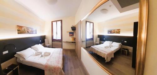 a reflection of a bedroom with two beds in a mirror at Albergo Trento in Verona