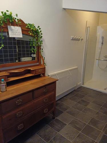 uma casa de banho com uma cómoda com um espelho e um chuveiro em Black Pearl Apartment New Brighton em Wallasey